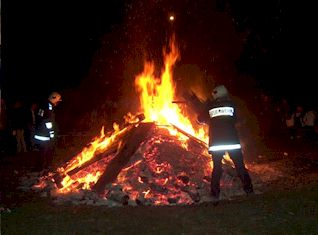 Osterfeuer in der Dunkelheit, Kameraden mit Geräten direkt am Feuer